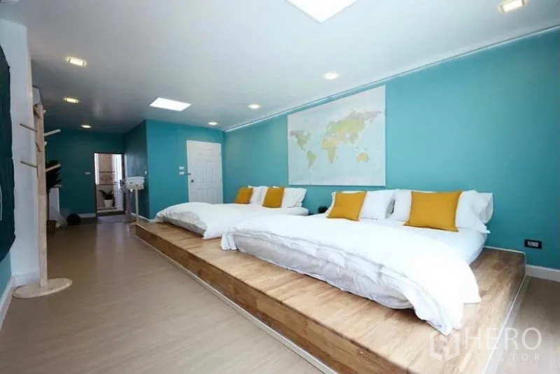 Townhouse for rent in Ratchathewi, Bangkok - Spacious bedroom with raised platform beds, teal accent walls and recessed lighting.