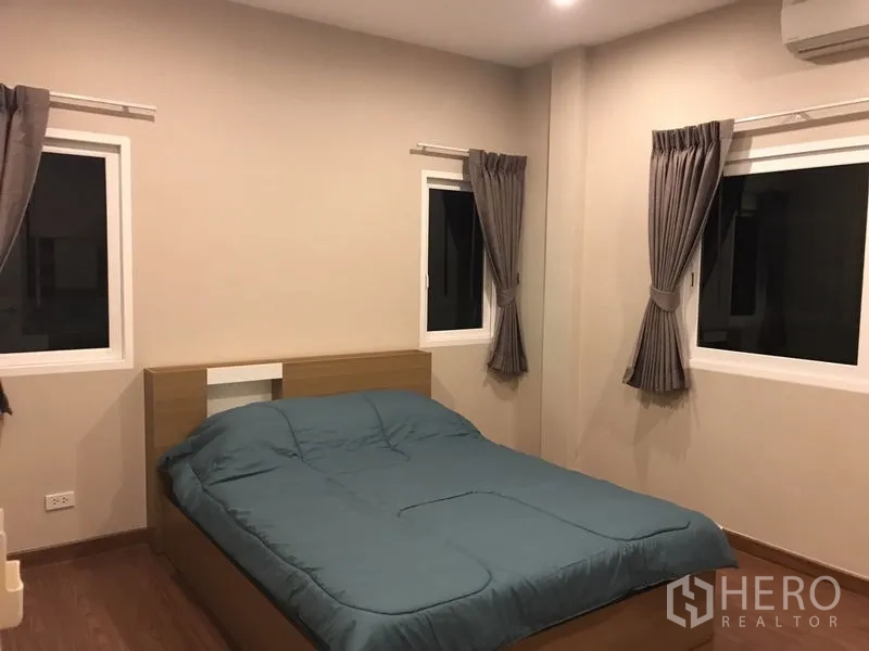 Detached House for rent or sale in Bang Na, Bangkok - Guest bedroom with teal duvet, corner windows and blackout curtains.