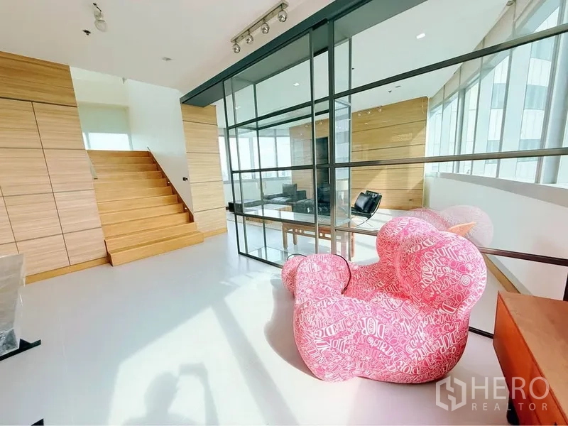 คอนโด ให้เช่าหรือขายในKhlong Toei, Bangkok - โถงสว่าง มีผนังกระจกกั้น บันไดไม้ และเก้าอี้เลานจ์สีชมพูทรงสนุก
