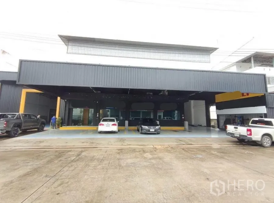 Warehouse for rent in Bang Phli, Samut Prakan - Modern black warehouse facade with wide covered loading bay and front parking.
