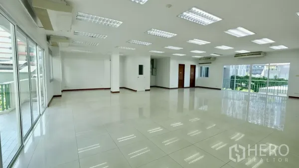Office Space for rent - Large bright office floor with multiple doors, LED lighting, and balcony access via sliding glass panels.
