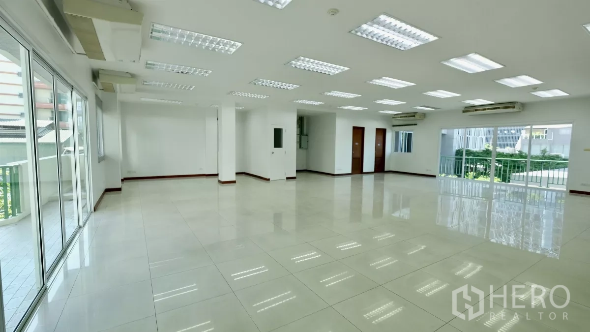 Office Space for rent - Large bright office floor with multiple doors, LED lighting, and balcony access via sliding glass panels.