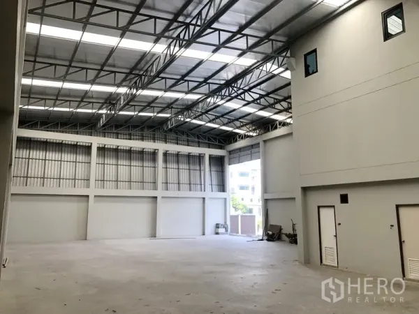 Factory for rent or sale in Bang Bua Thong, Nonthaburi - Clear-span warehouse space with bright skylights and truck entry point.
