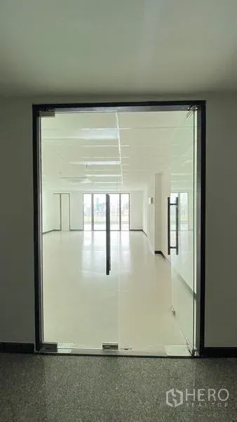 Office Space for rent in Watthana, Bangkok - Glass double doors open to a bright open-plan office with white walls and a dropped ceiling.