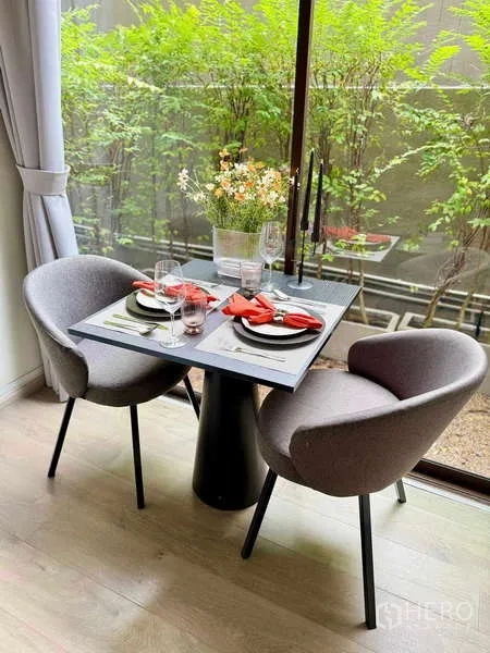 Condominium for rent - Compact dining nook for two by a floor-to-ceiling window framed by greenery.