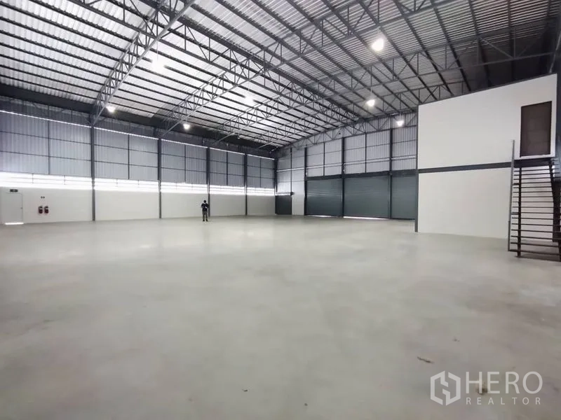 Warehouse for rent in Bang Phli, Samut Prakan - Clear-span floor area with steel stair to mezzanine office and large loading doors.