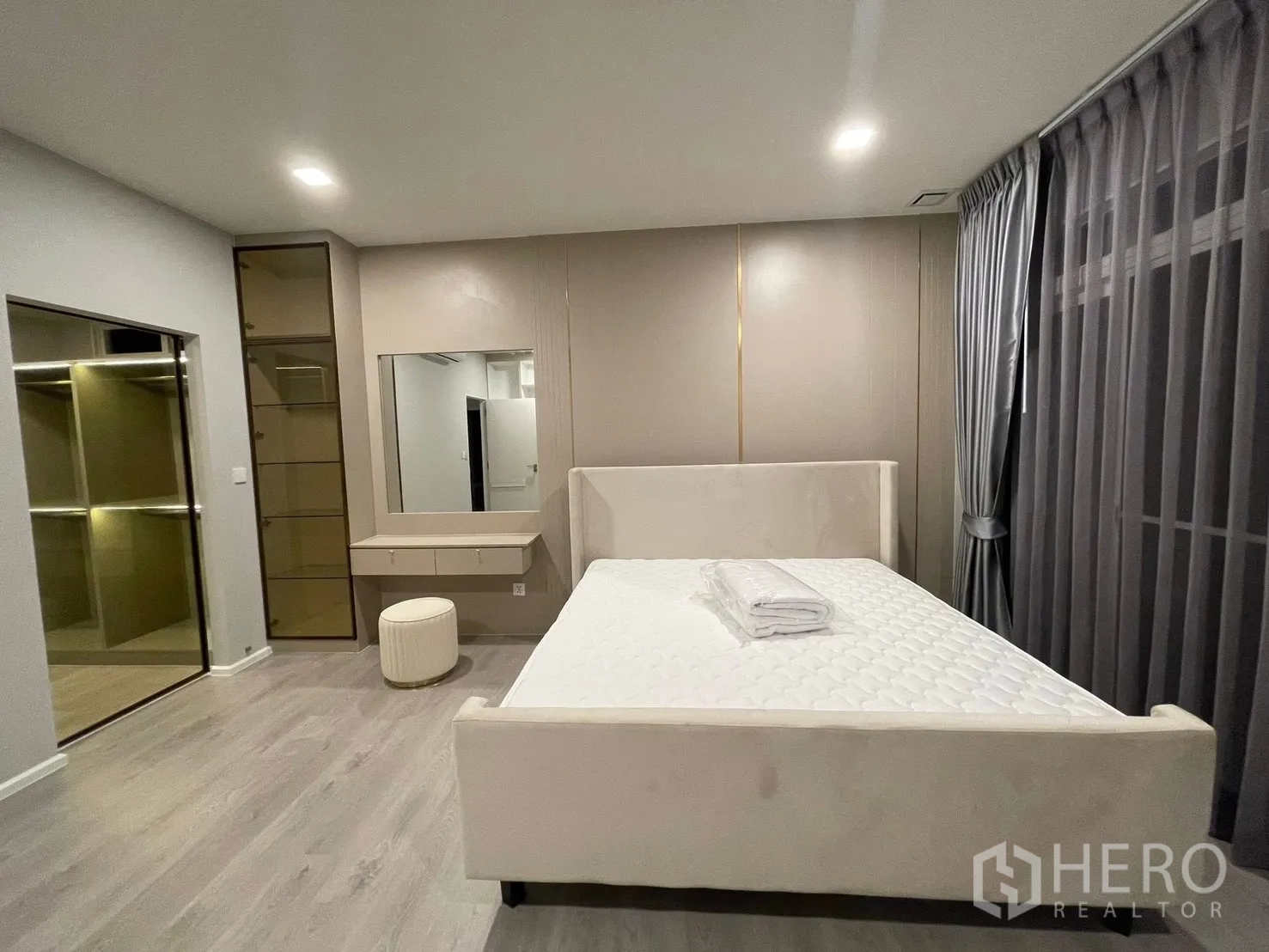 Detached House for rent in Prawet, Bangkok - Bedroom with upholstered bed, vanity, and walk-in closet with glass doors.