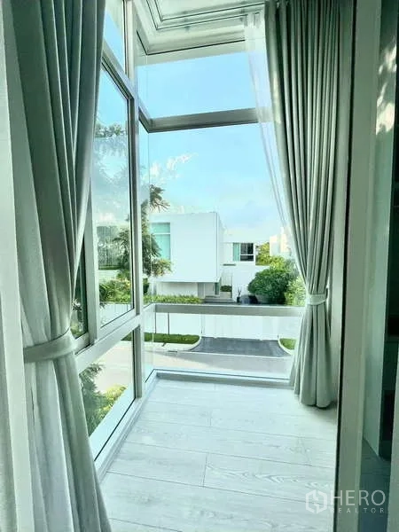 独立式住宅 出租或出售在Bang Phli, Samut Prakan - 转角落地窗配长帘，俯瞰宁静街景。