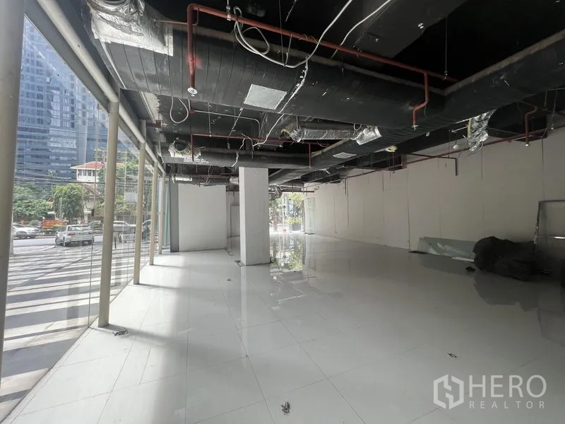 零售空间 出租在Watthana, Bangkok - 零售铺位毛坯内景，落地窗、亮面地砖与外露管线天花。