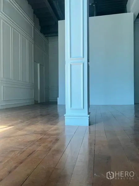 零售空间 出租在Khlong Toei, Bangkok - 开阔零售大厅，中央白色立柱，墙面线条装饰与实木地板