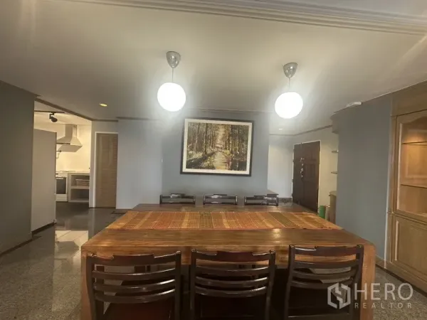 คอนโด ขายในWatthana, Bangkok - มุมรับประทานอาหาร โต๊ะไม้ยาว โคมไฟห้อย และทางเข้าครัวแยก