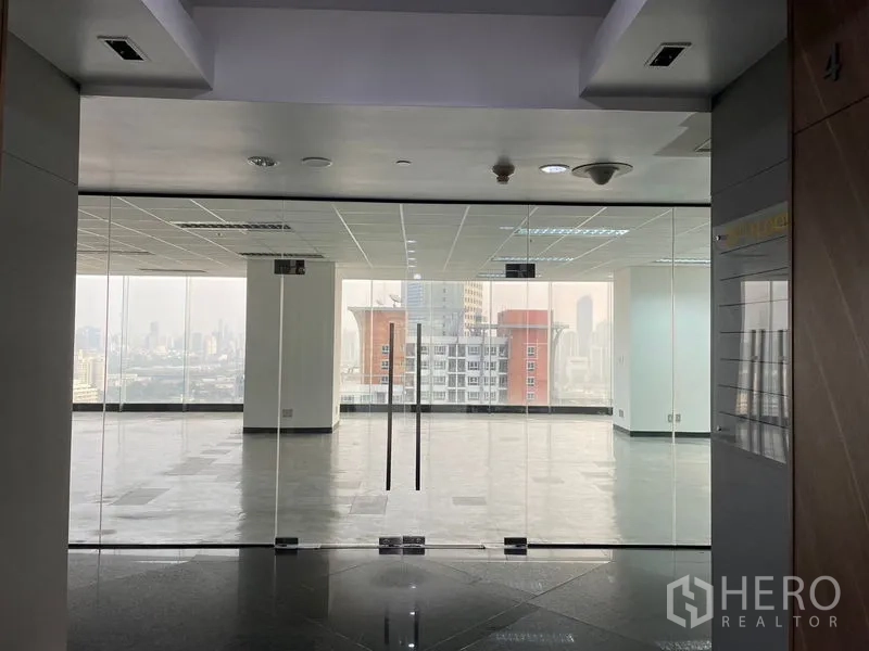 办公空间 出租在Din Daeng, Bangkok - 玻璃双扇门办公室入口，背景为城市天际线。