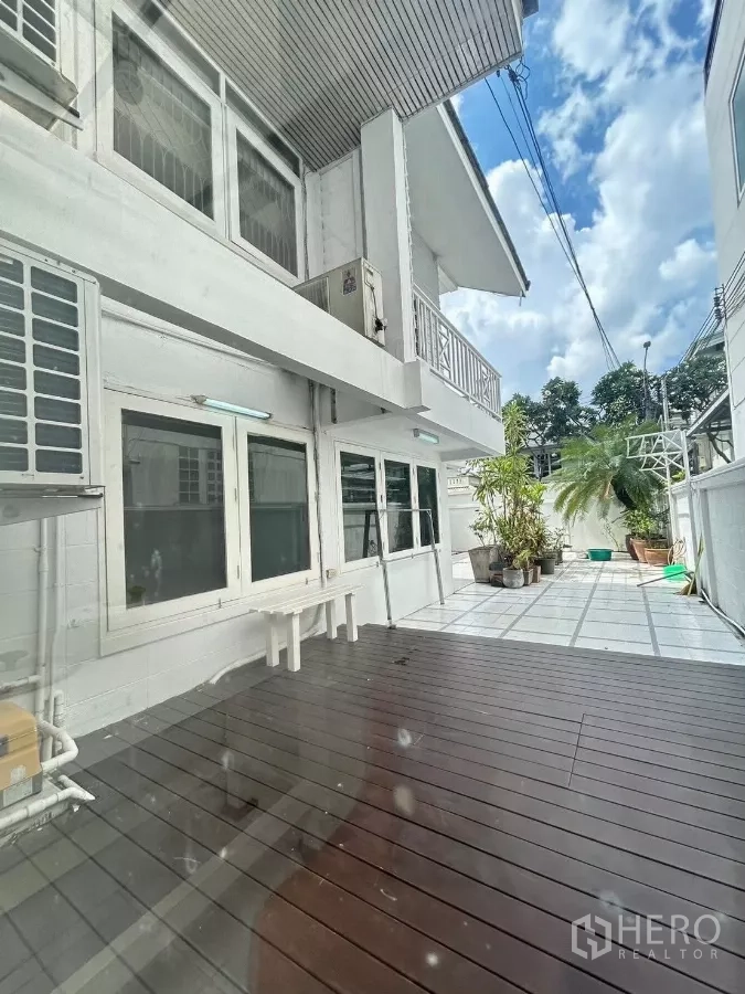 Detached House for rent in Suan Luang, Bangkok - Sunlit side patio with a wood deck and tiled yard beside the white house.