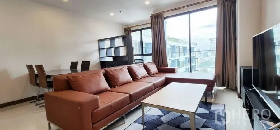 Condominium for rent - Living area with sectional sofa, coffee table, rug and panoramic windows bringing in daylight.
