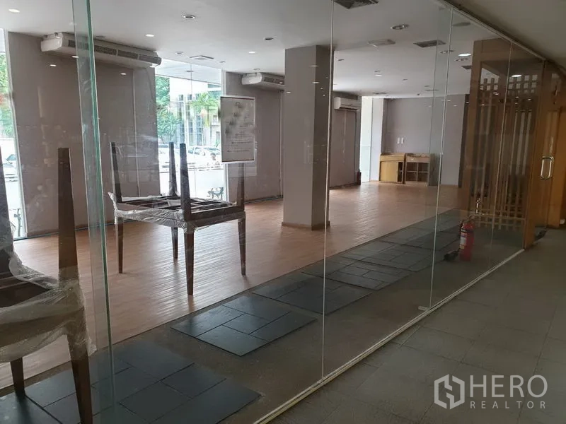 零售空间 出租在Khlong Toei, Bangkok - 临街整面玻璃店面，室内明亮可见木地板。