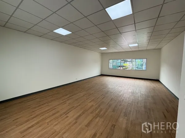 พื้นที่ขายปลีก ให้เช่า - ห้องค้าปลีกโล่งกว้าง พื้นลายไม้ ผนังสีขาว ฝ้าทีบาร์พร้อมไฟ และหน้าต่าง