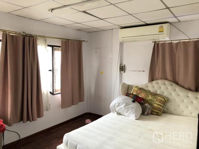 独立式住宅 出售在Pak Kret, Nonthaburi - 主卧带多扇窗、窗帘与空调，软包床头。