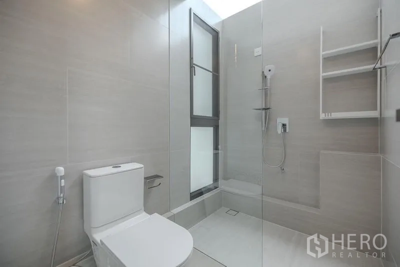 Detached House for rent in Saphan Sung, Bangkok - Bright bathroom with glass shower enclosure, toilet and window.