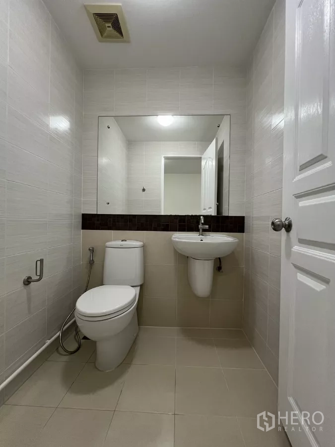Townhouse for rent in Bang Kapi, Bangkok - Guest bathroom with toilet, sink and wall mirror.