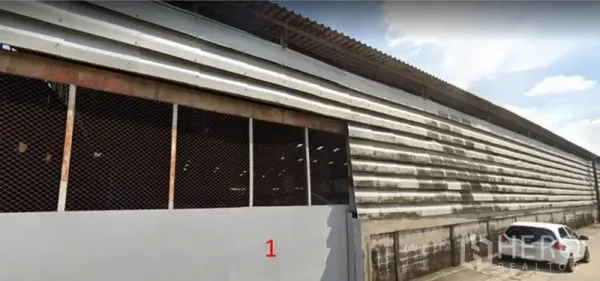 Warehouse for rent in Bang Khun Thian, Bangkok - Close-up of the warehouse facade with sliding metal gate and parking area beside the building.