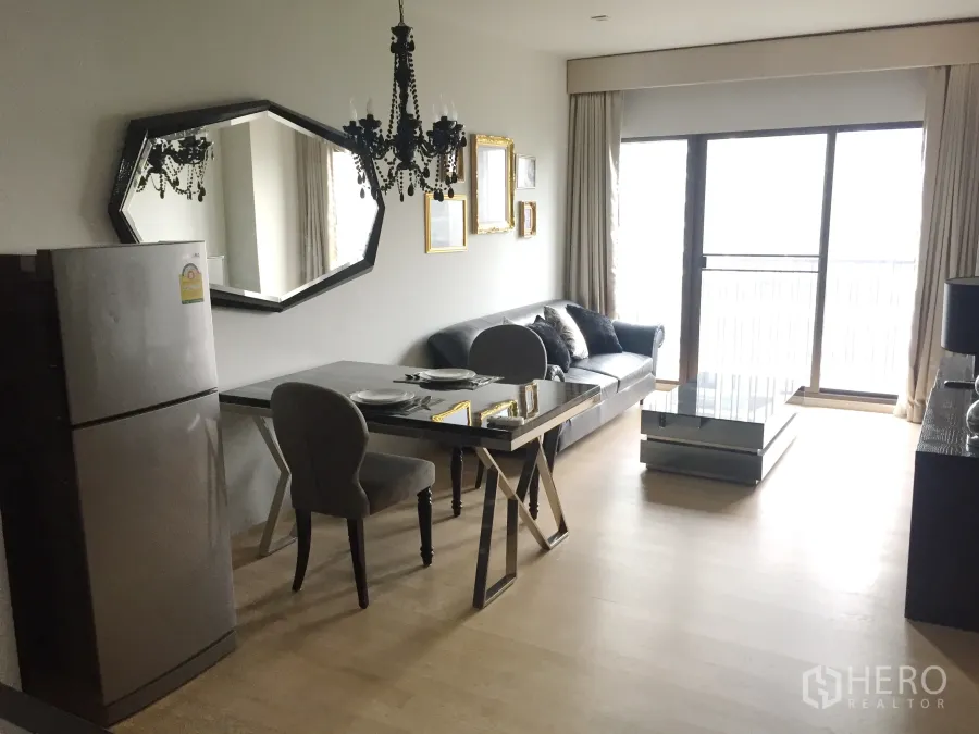 คอนโด ให้เช่าในBangkok - พื้นที่นั่งเล่น–ทานข้าวสว่าง โคมระย้า กระจกเงาบานใหญ่ โซฟา โต๊ะอาหาร และประตูกระจกออกสู่ระเบียง