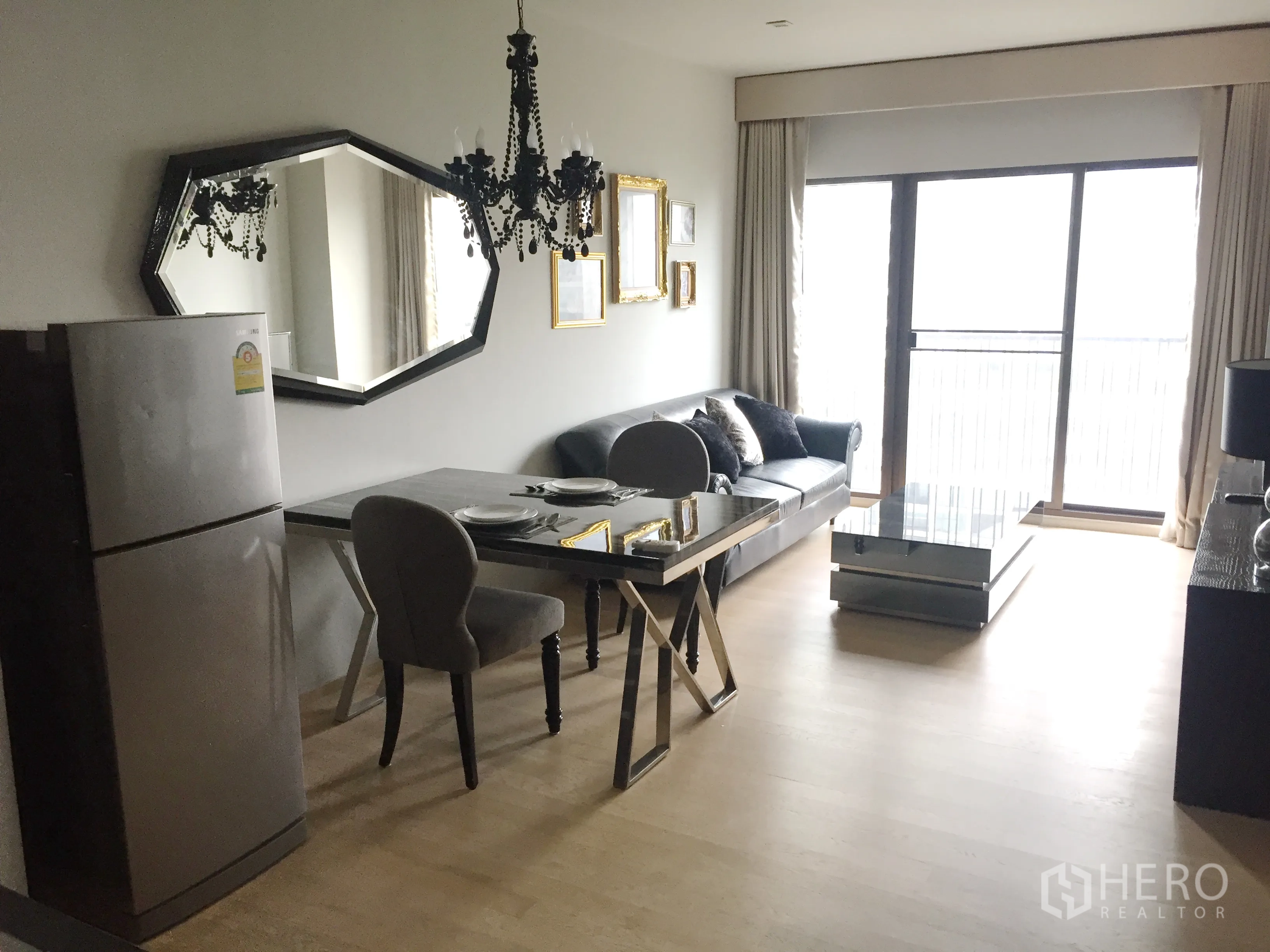 คอนโด ให้เช่าในBangkok - พื้นที่นั่งเล่น–ทานข้าวสว่าง โคมระย้า กระจกเงาบานใหญ่ โซฟา โต๊ะอาหาร และประตูกระจกออกสู่ระเบียง