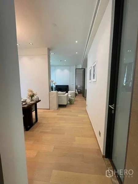 Condominium for rent in Pathum Wan, Bangkok - Wide hallway with light wood flooring leading to the living and dining spaces.