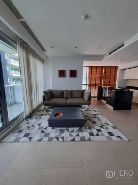 คอนโด ให้เช่าหรือขายในKhlong San, Bangkok - พื้นที่รับแขกพร้อมโซฟา พรมลายเรขาคณิต โต๊ะกลาง และประตูกระจกสไลด์ออกระเบียง