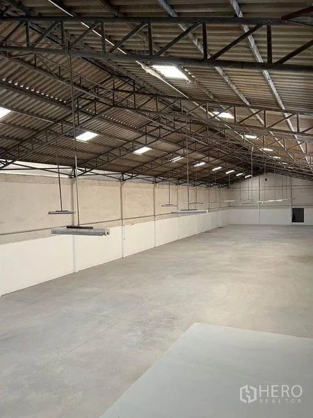 Warehouse for rent in Khlong Toei, Bangkok - Steel truss roof with hanging lights over an open storage floor.