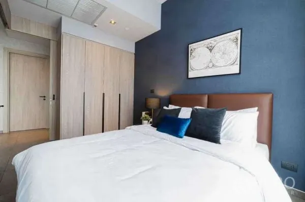 Condominium for rent in Watthana, Bangkok - Cozy bedroom with blue accent wall, padded headboard and built-in wardrobes.