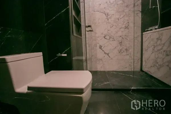 公寓 出租或出售在Watthana, Bangkok - 现代卫浴，黑色大理石墙地、坐便器与玻璃淋浴间。