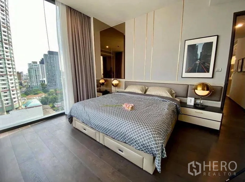 Condominium for rent in Watthana, Bangkok - Master bedroom with king bed, bedside lamps and floor-to-ceiling window with Bangkok city view.