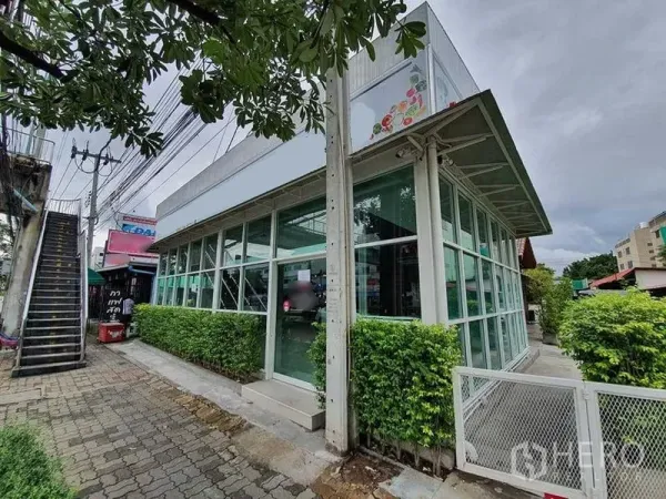 พื้นที่ขายปลีก ให้เช่าในPrawet, Bangkok - อาคารมุมผนังกระจก ล้อมด้วยรั้วต้นไม้ ติดทางเท้าและบันไดลอยฟ้า