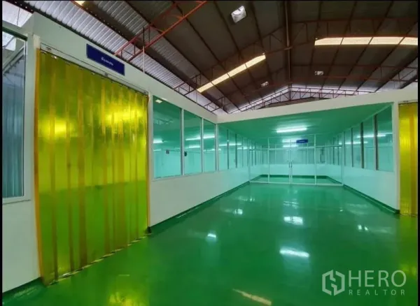 Factory for sale in Chon Buri - Corridor with glass-partitioned rooms and yellow PVC strip curtains