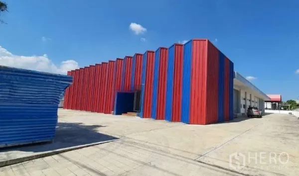 工厂 出租或出售在Lat Krabang, Bangkok - 红蓝配色工厂转角外观，配大面积车道与停车空间。