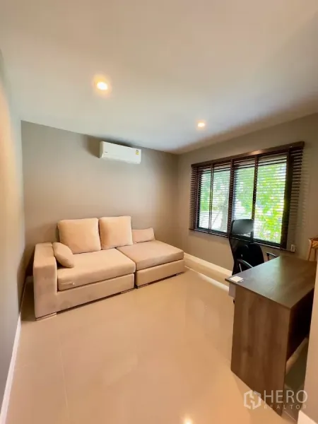 独立式住宅 出租在Samut Prakan - 多功能房布置为书房，配沙发、书桌和百叶窗。