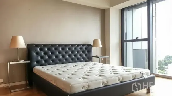 Condominium for rent or sale in Sathon, Bangkok - Spacious bedroom with tufted leather headboard and tall window offering an urban view.