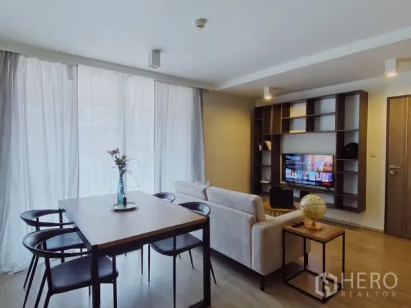 คอนโด ให้เช่าในPathum Wan, Bangkok - พื้นที่นั่งเล่นและรับประทานอาหารสว่างด้วยผ้าม่านโปร่ง โซฟา โต๊ะสี่ที่นั่ง และชั้นวางบิลท์อินพร้อมทีวี