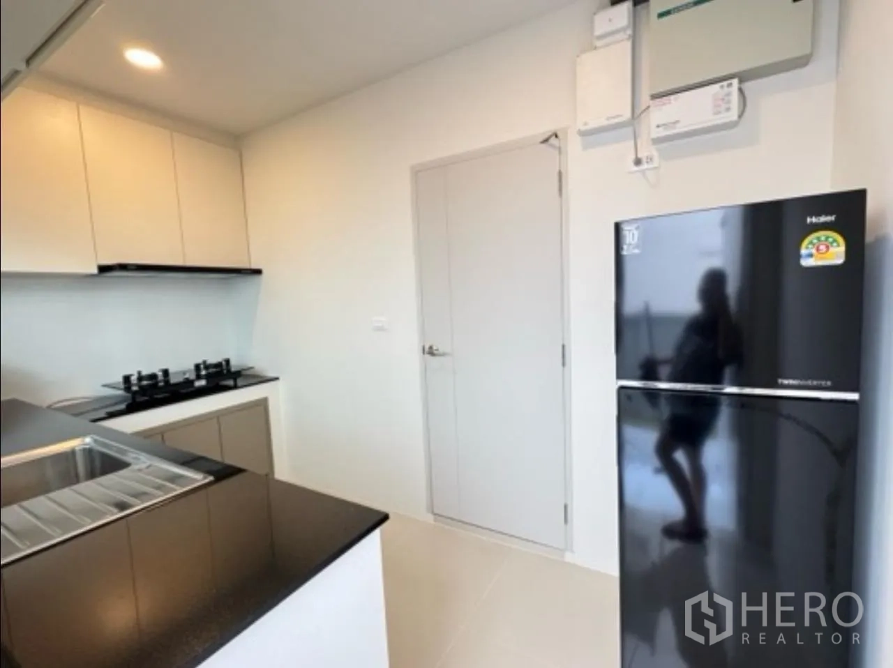 独栋房屋 for rent in Bang Phli, Samut Prakan - 厨房一角，带冰箱、房门与吊柜。