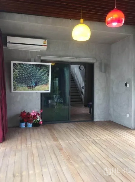 Detached House for sale in Pak Kret, Nonthaburi - Covered terrace featuring a wooden deck, colorful pendant lamps and a sliding glass doorway.