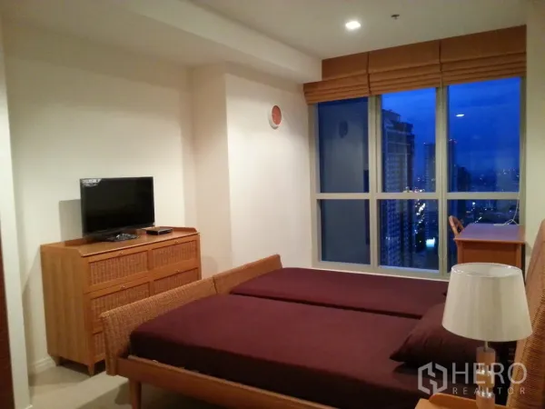 คอนโด ขายในKhlong San, Bangkok - ห้องนอนคอนโด คลองสาน กรุงเทพฯ เตียงหวาย ตู้ลิ้นชัก ทีวี และหน้าต่างบานใหญ่เห็นวิวเมืองยามค่ำ