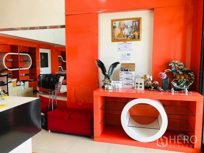 Shophouse for rent or sale in Bang Khun Thian, Bangkok - Close-up of an orange display cabinet and counter with decorative items and glass shelving.