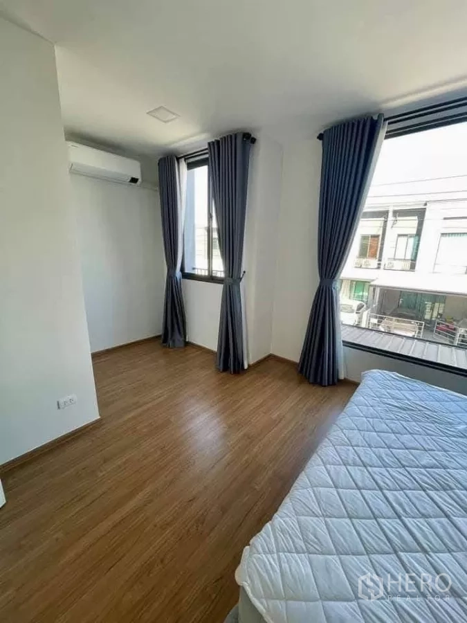 Townhouse for rent in Bang Phli, Samut Prakan - Corner bedroom with multiple windows, gray curtains and laminate floor.