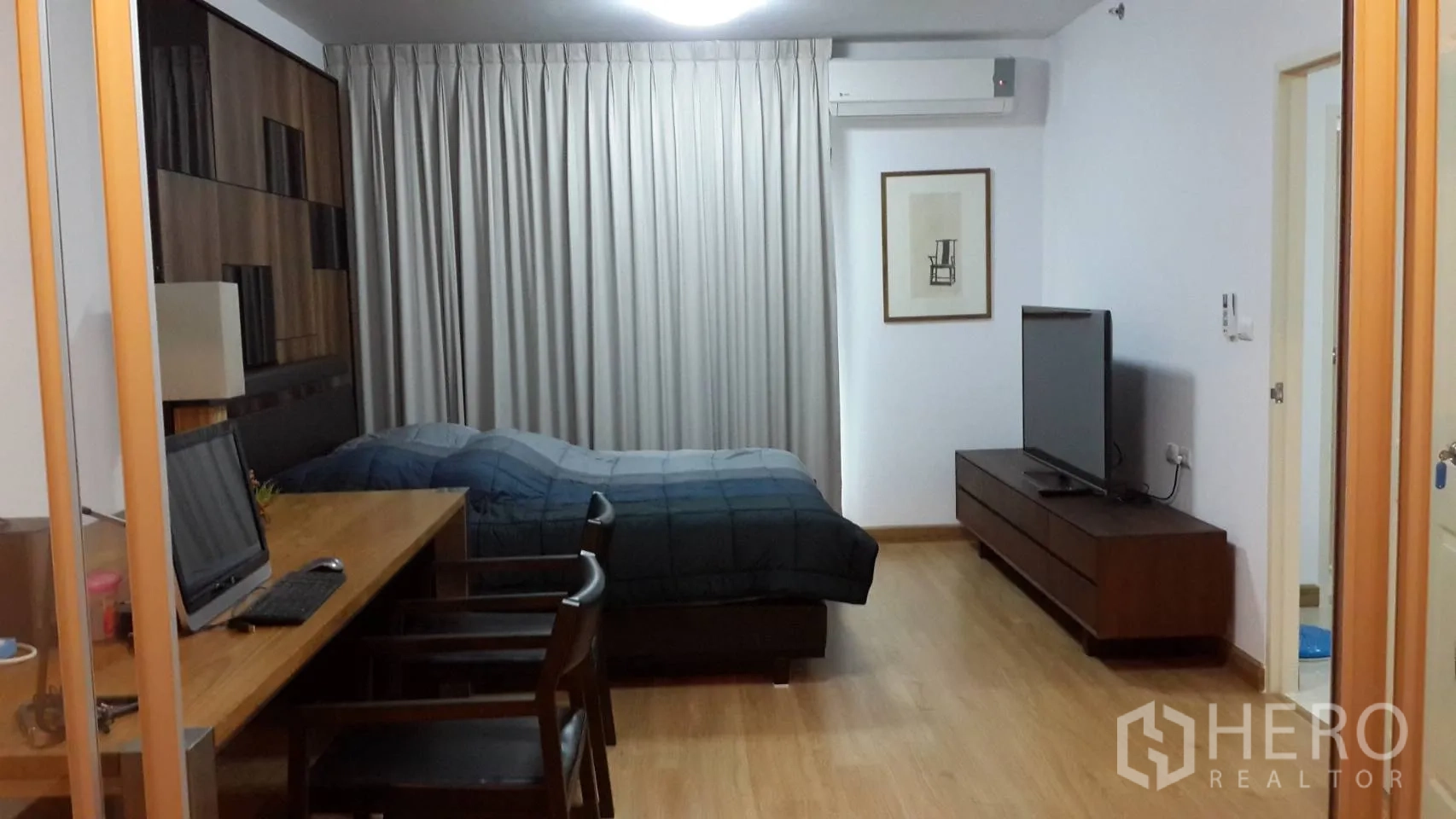 คอนโด ให้เช่าในHuai Khwang, Bangkok - พื้นที่นั่งเล่น-นอนพื้นไม้ โทนอบอุ่น พร้อมเตียง โต๊ะทำงานยาว ตู้วางทีวี ผ้าม่าน และเครื่องปรับอากาศ