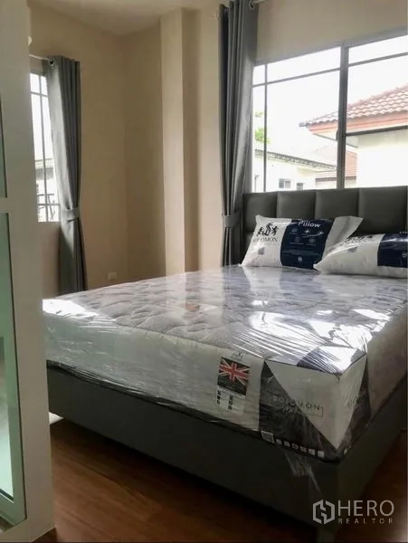 Detached House for rent in Prawet, Bangkok - Sunlit bedroom with queen bed and corner windows.