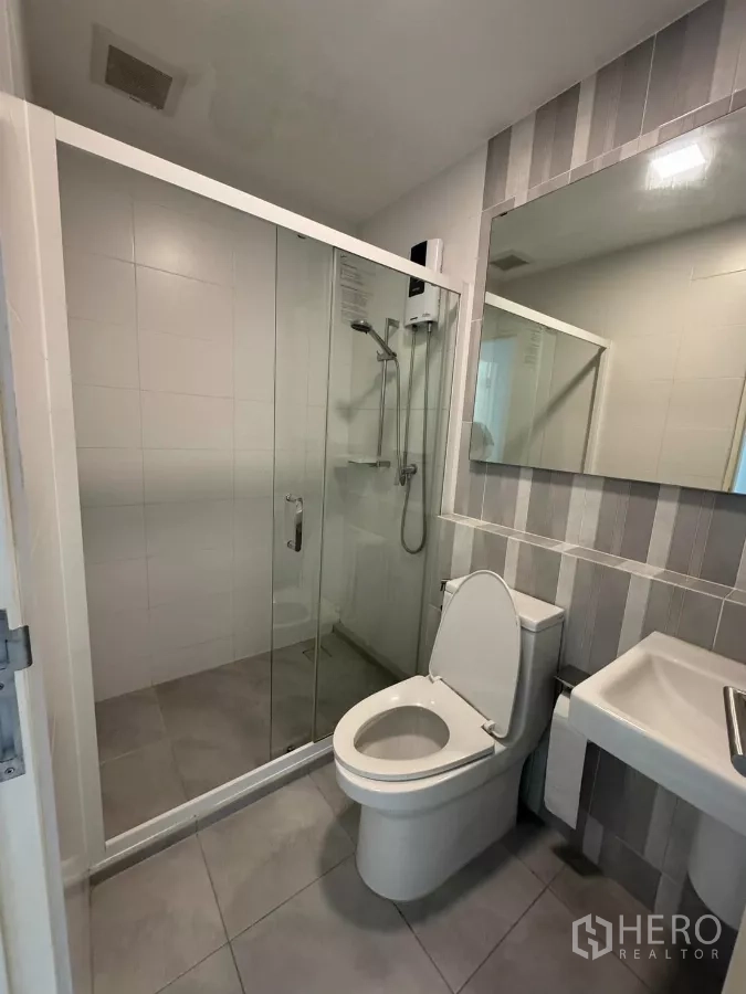 Townhouse for rent in Bang Phli, Samut Prakan - Modern bathroom with glass-enclosed shower, gray tiles, and vanity.
