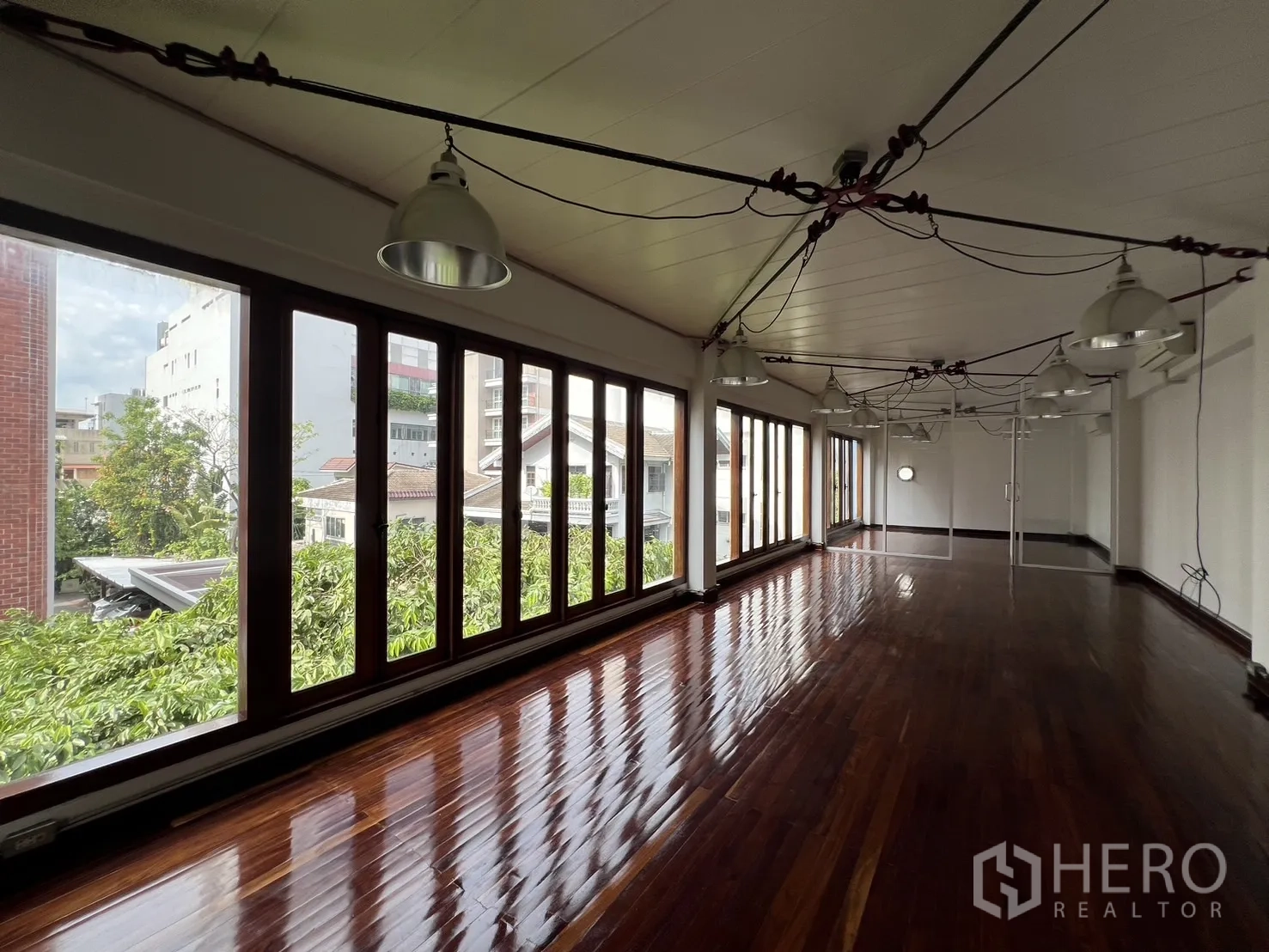 สำนักงานที่บ้าน ให้เช่าในWatthana, Bangkok - พื้นที่ทำงานแบบโอเพ่นสเปซ พื้นไม้ขัดเงา ผนังกระจกยาว และโคมไฟแขวนสไตล์อุตสาหกรรม.