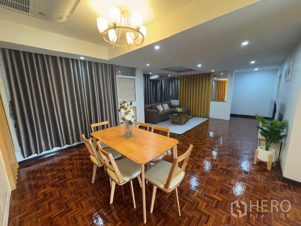 Condominium for rent in Huai Khwang, Bangkok - Wide open-plan living and dining area with full-length curtains, chandelier and glossy parquet floors.