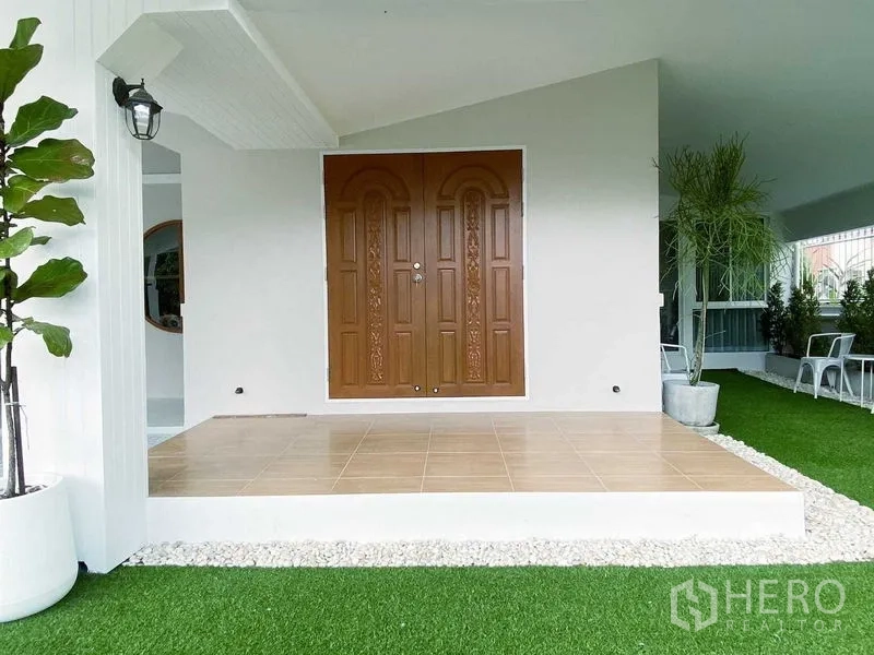 บ้าน ให้เช่าในLam Luk Ka, Pathum Thani - เฉลียงหน้าบ้านมุงหลังคา พื้นกระเบื้อง และประตูไม้บานคู่แกะสลัก