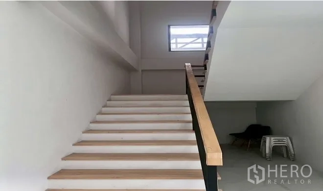 Warehouse for rent in Bang Bo, Samut Prakan - Interior staircase with handrail leading to the upper office level and a small window on the landing.